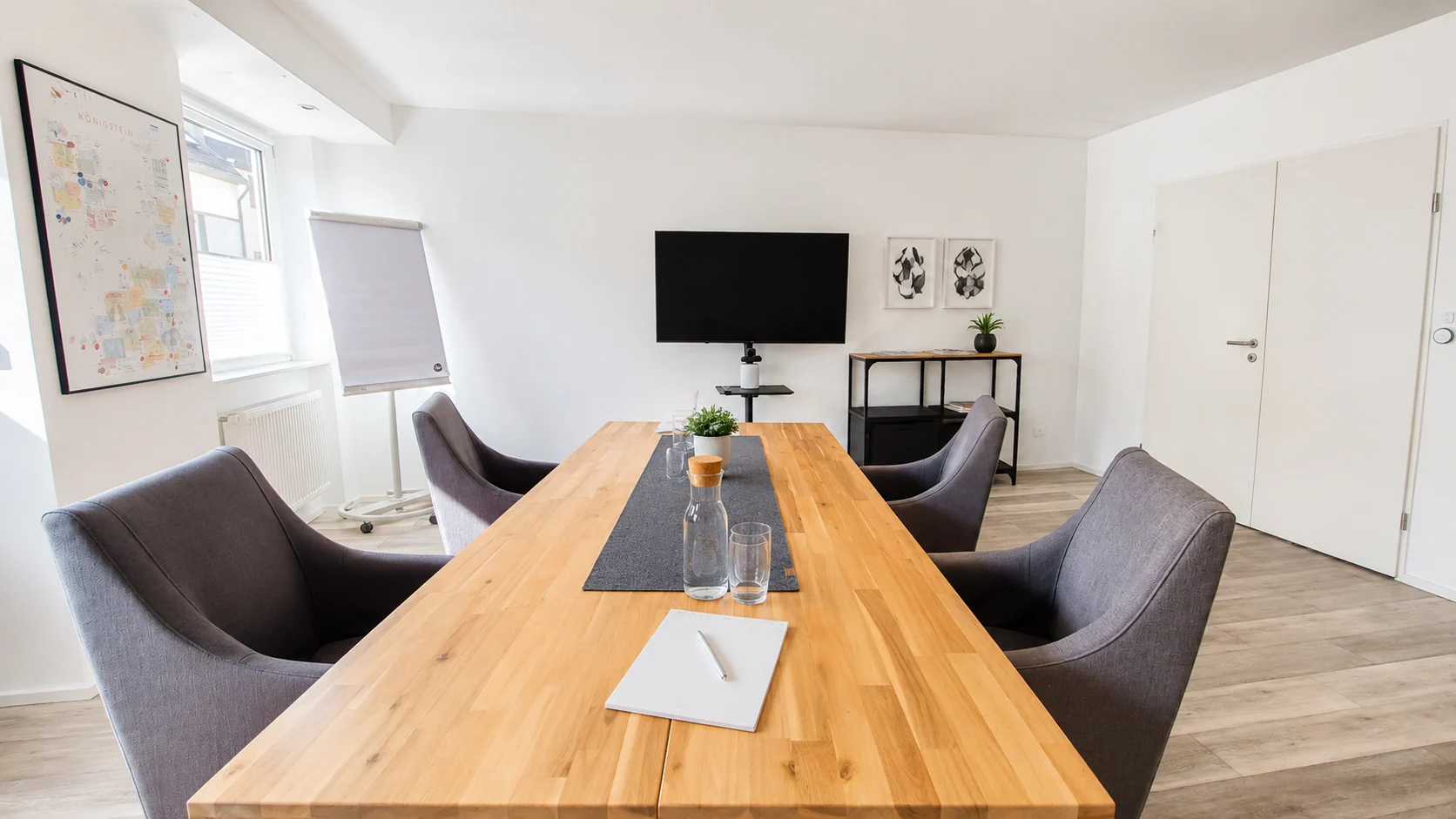 Heller, vorbereiteter Konferenzraum mit großem Holztisch, Display und Whiteboard als repräsentativer Besprechungsraum im K7 Workspace Königstein